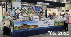 he Quilt Direct stand at the Festival of Quilts 2025, featuring AccuQuilt and Quilter's Rule branding, with team members demonstrating products to visitors at a busy exhibition hall.