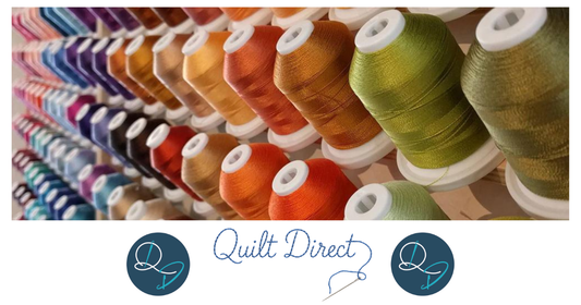 Rows of colourful embroidery thread spools on a display rack, featuring a vibrant spectrum of colours including purples, pinks, reds, oranges, golds and greens