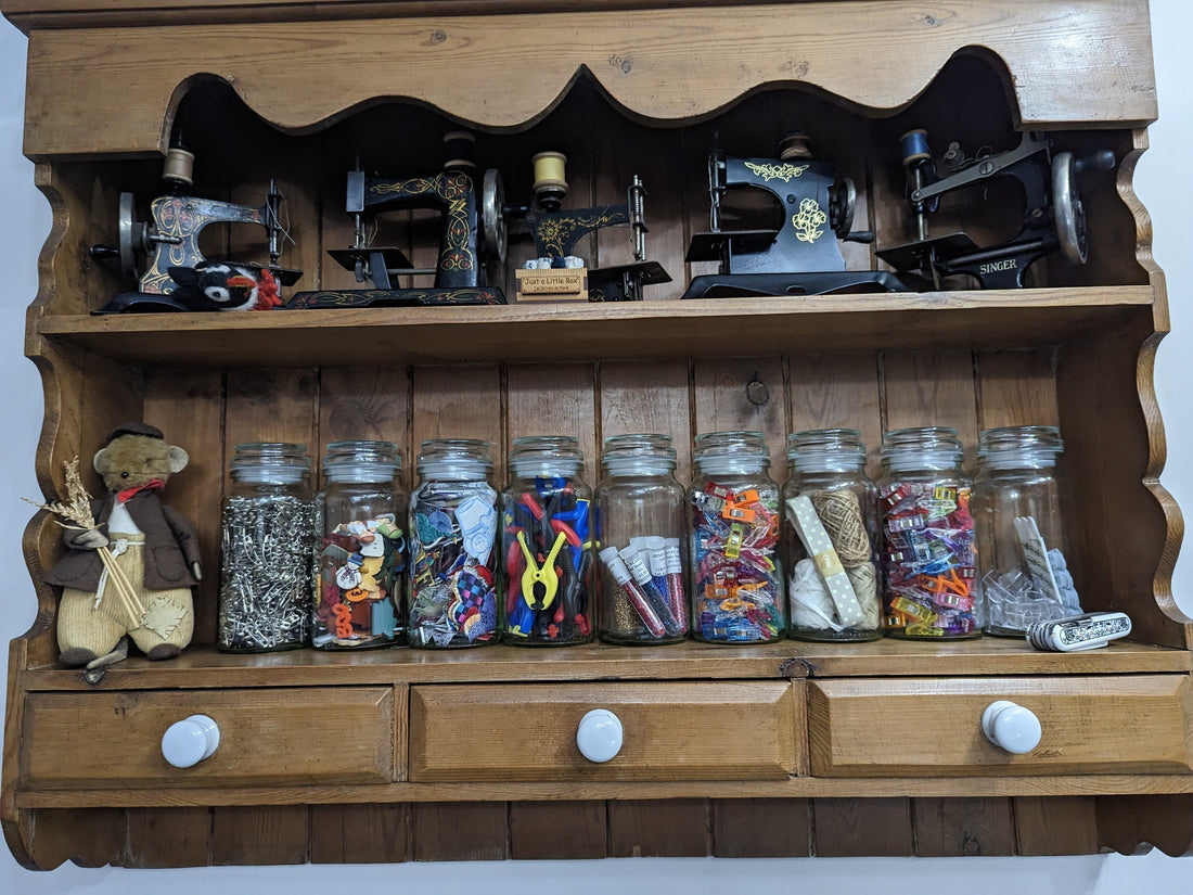Sewing room storage ideas including thread boxes, AccuQuilt die rack, and fabric stored upright on shelves