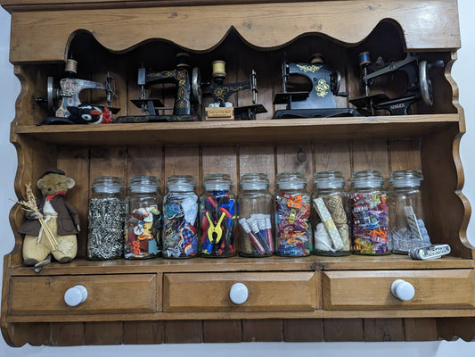 Sewing room storage ideas including thread boxes, AccuQuilt die rack, and fabric stored upright on shelves