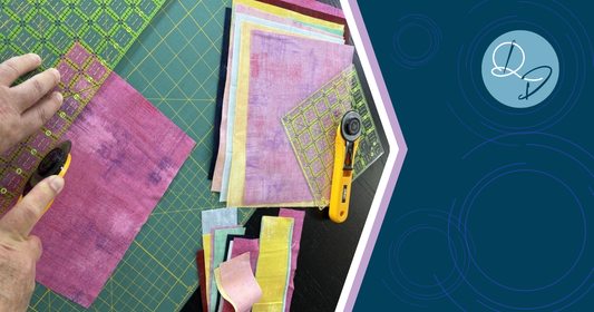 Rotary cutter, self-healing cutting mat and quilting ruler laid out on a cutting table, essential tools for accurate rotary cutting in quilting