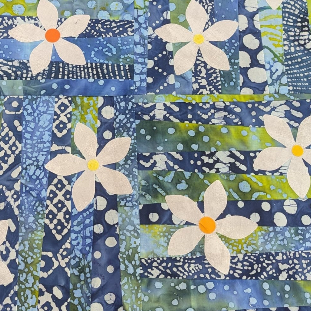 Machine Pieced and cut  daisy appliqué quilt in blue and green batik fabrics; patchwork and quilting tuition at Quilt Direct