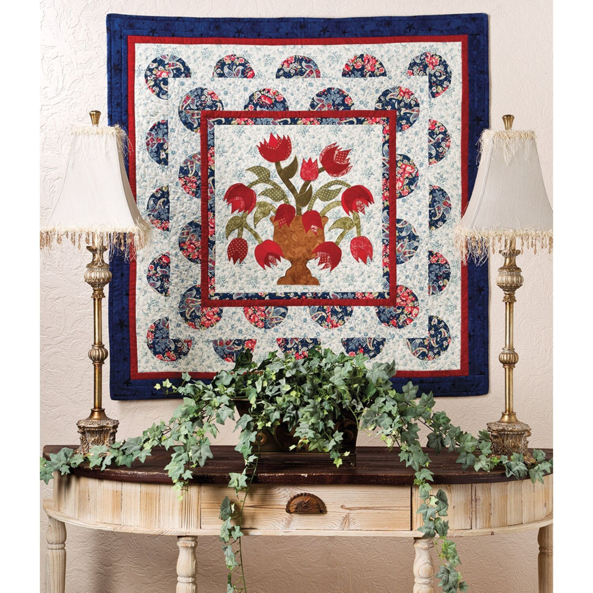 AccuQuilt GO! Feathers tulip-vase quilt hung on a wall above lamps and trailing ivy