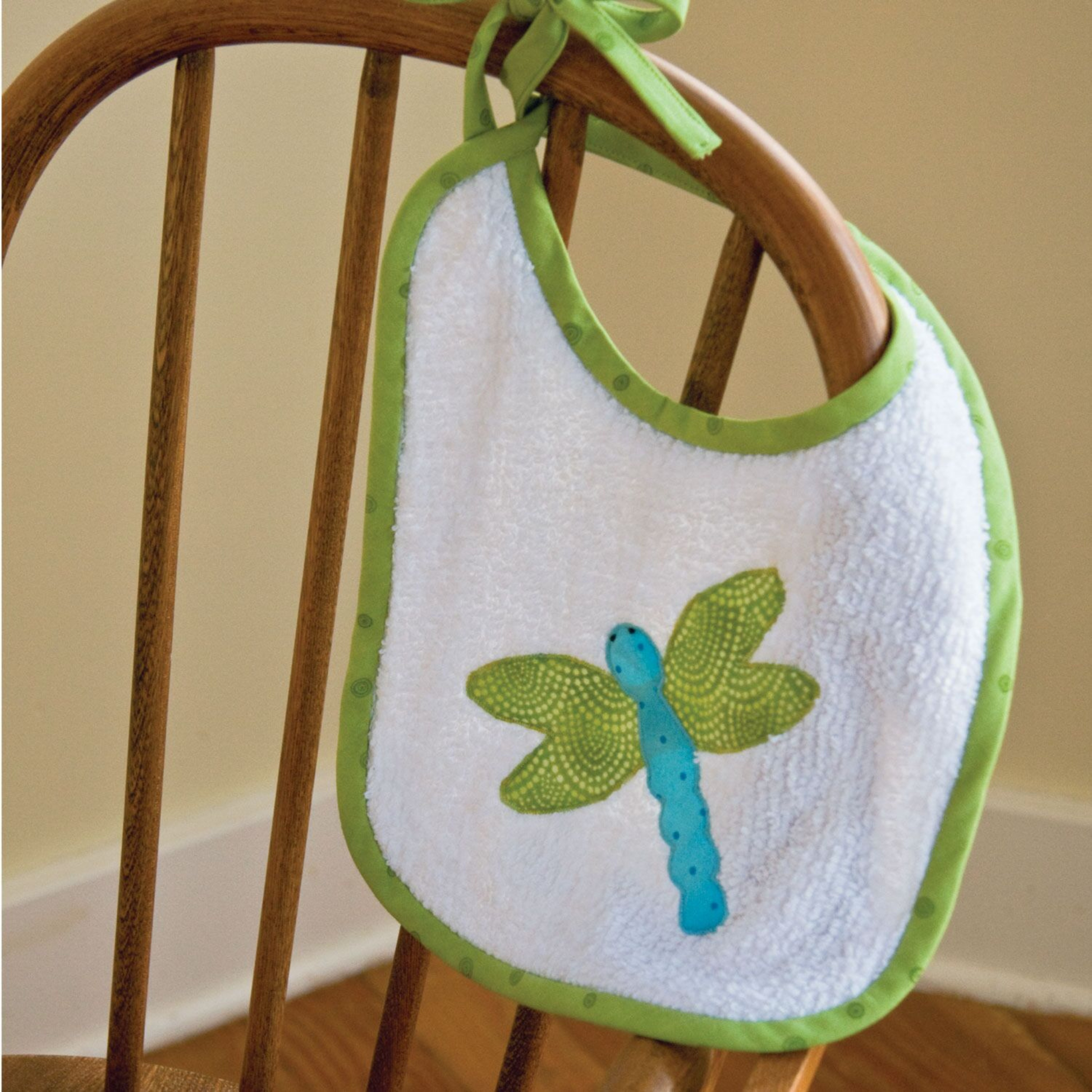 AccuQuilt GO! Critters dragonfly shape appliqued in green and blue on a white towelling baby bib
