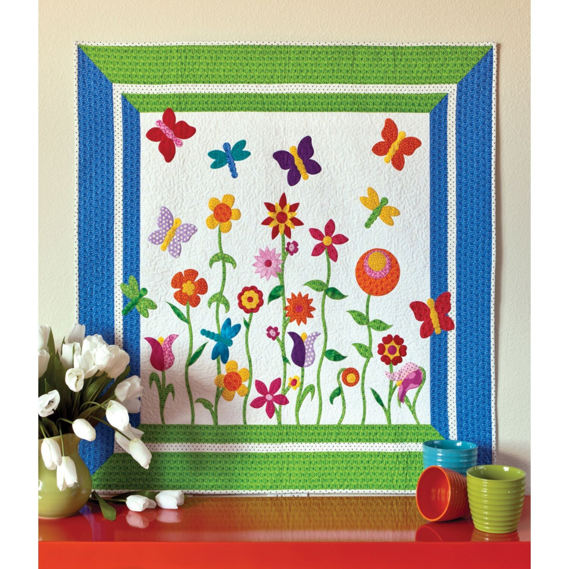 AccuQuilt GO! Critters garden quilt with a blue and green border, styled with tulips and cups