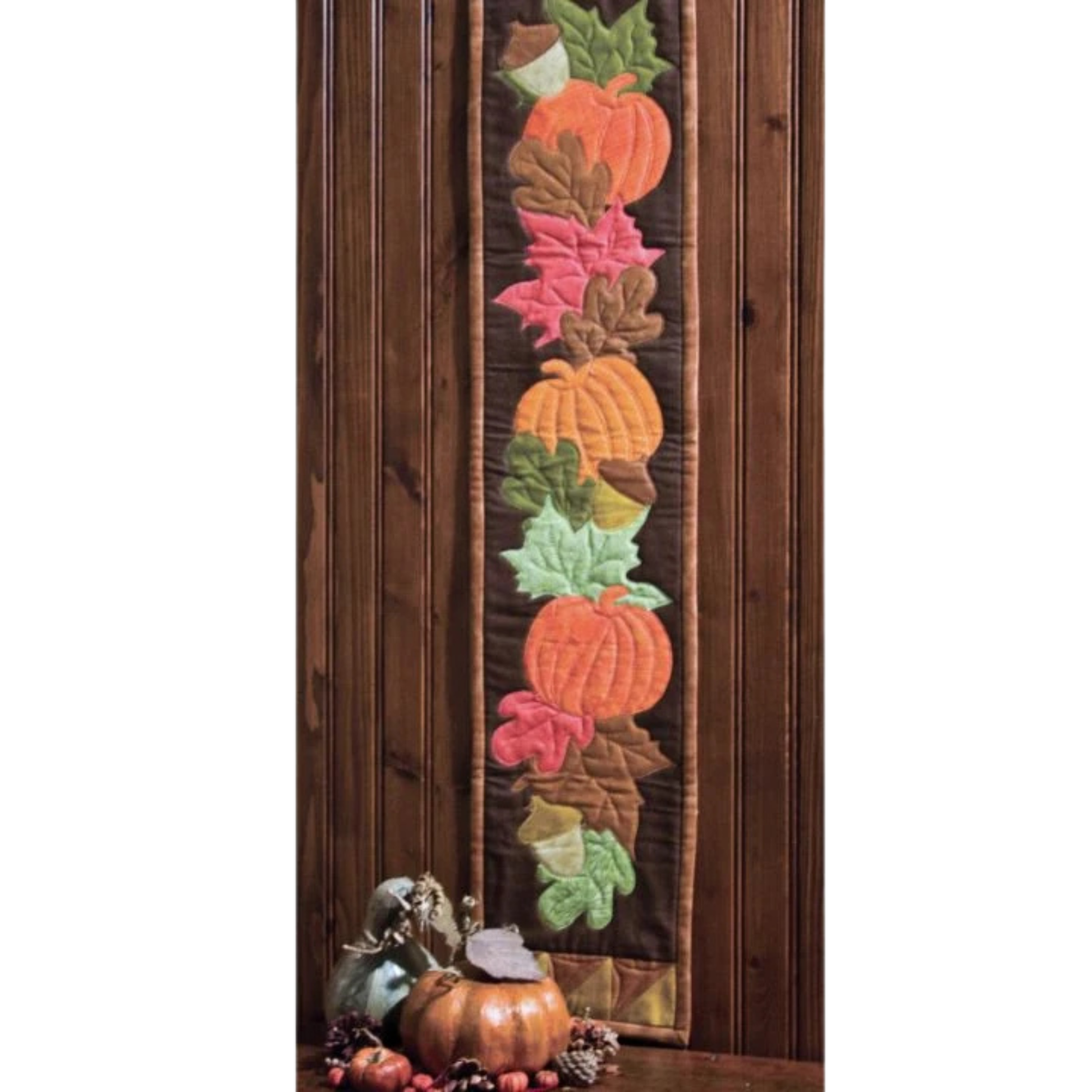 AccuQuilt GO! Fall Medley wall hanging with pumpkins and leaves, hung on wood panelling with gourds