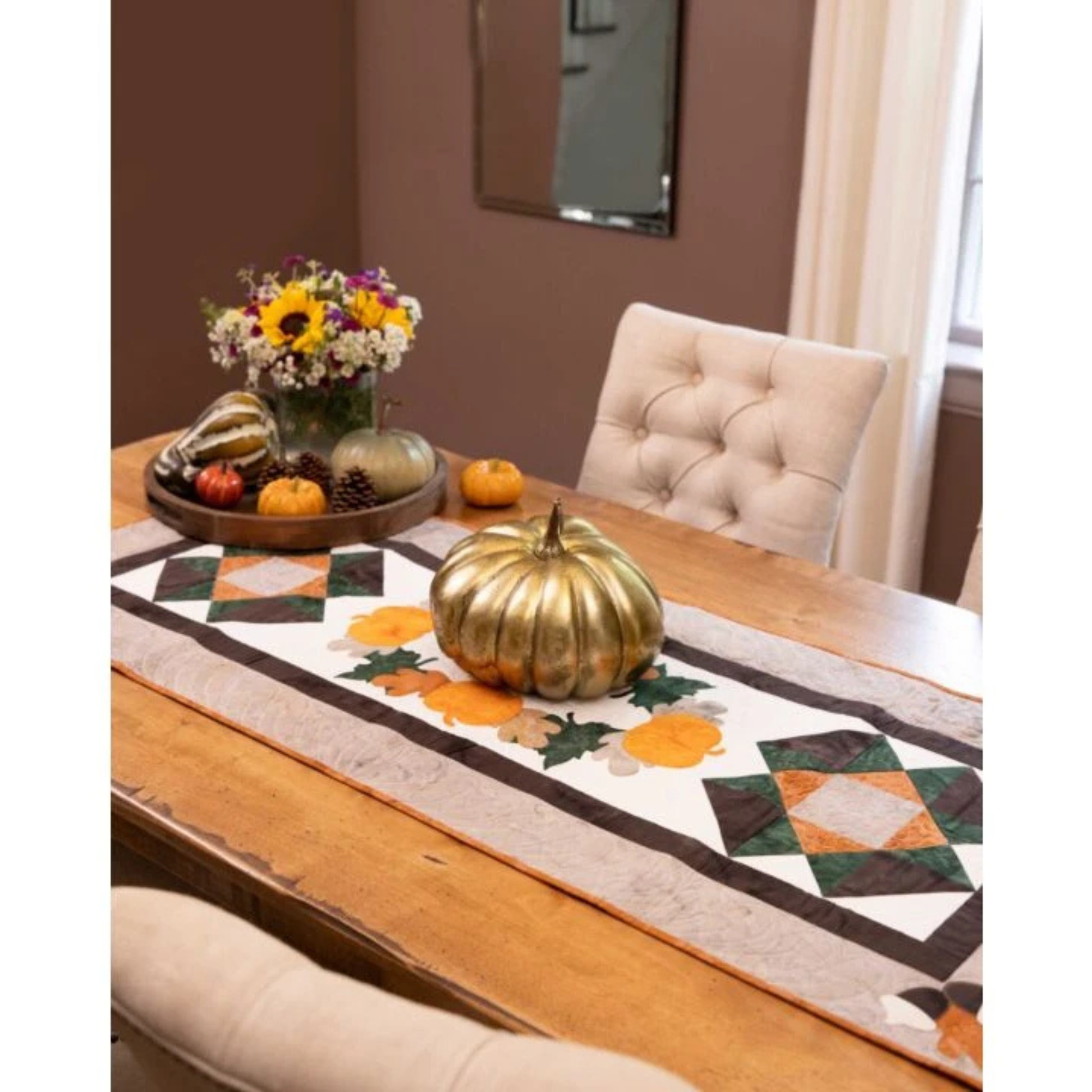 AccuQuilt GO! Fall Medley table runner with pieced stars, styled with a gold pumpkin and flowers