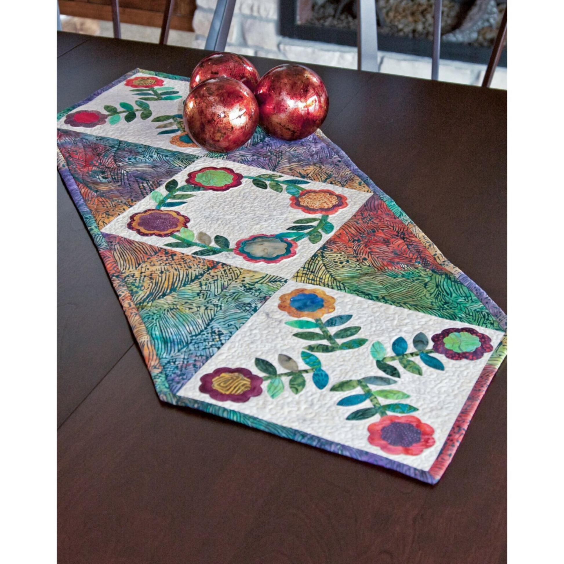AccuQuilt GO! Rose of Sharon table runner with layered roses, styled with red decorative spheres