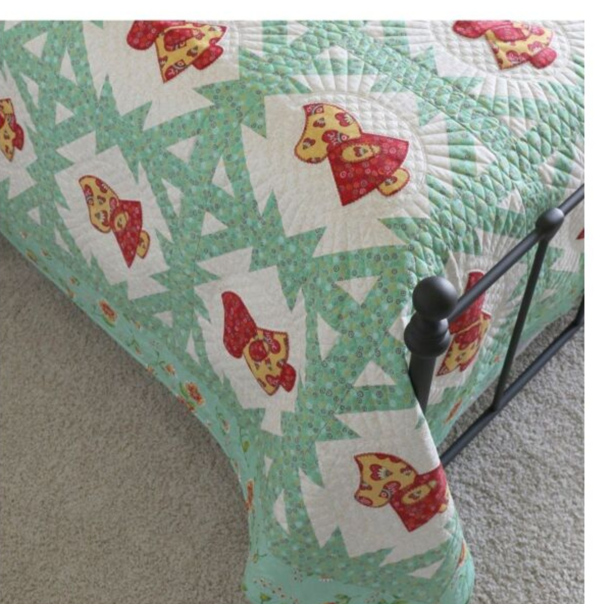 AccuQuilt GO! Sunbonnet Sue red and yellow quilt draped over the corner of an iron bed frame