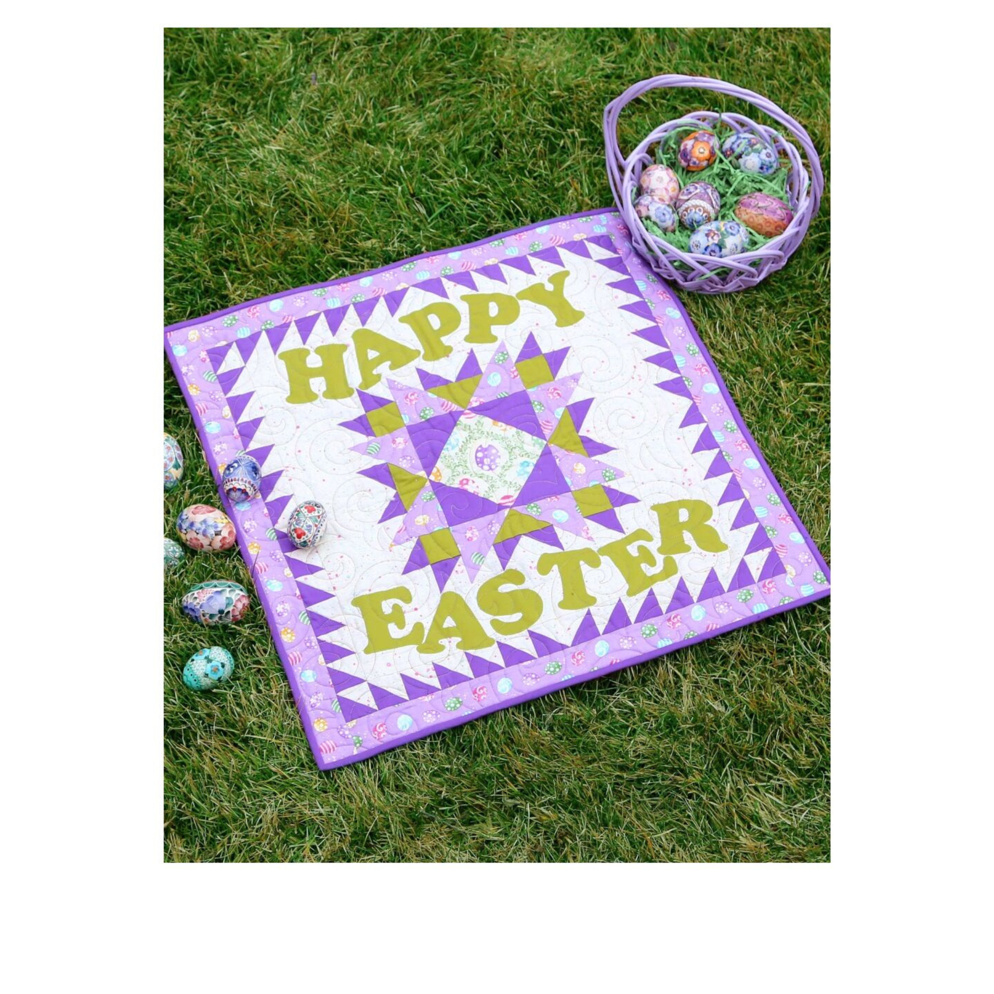 Happy Easter quilt with a purple and olive star block, styled on grass with an egg basket