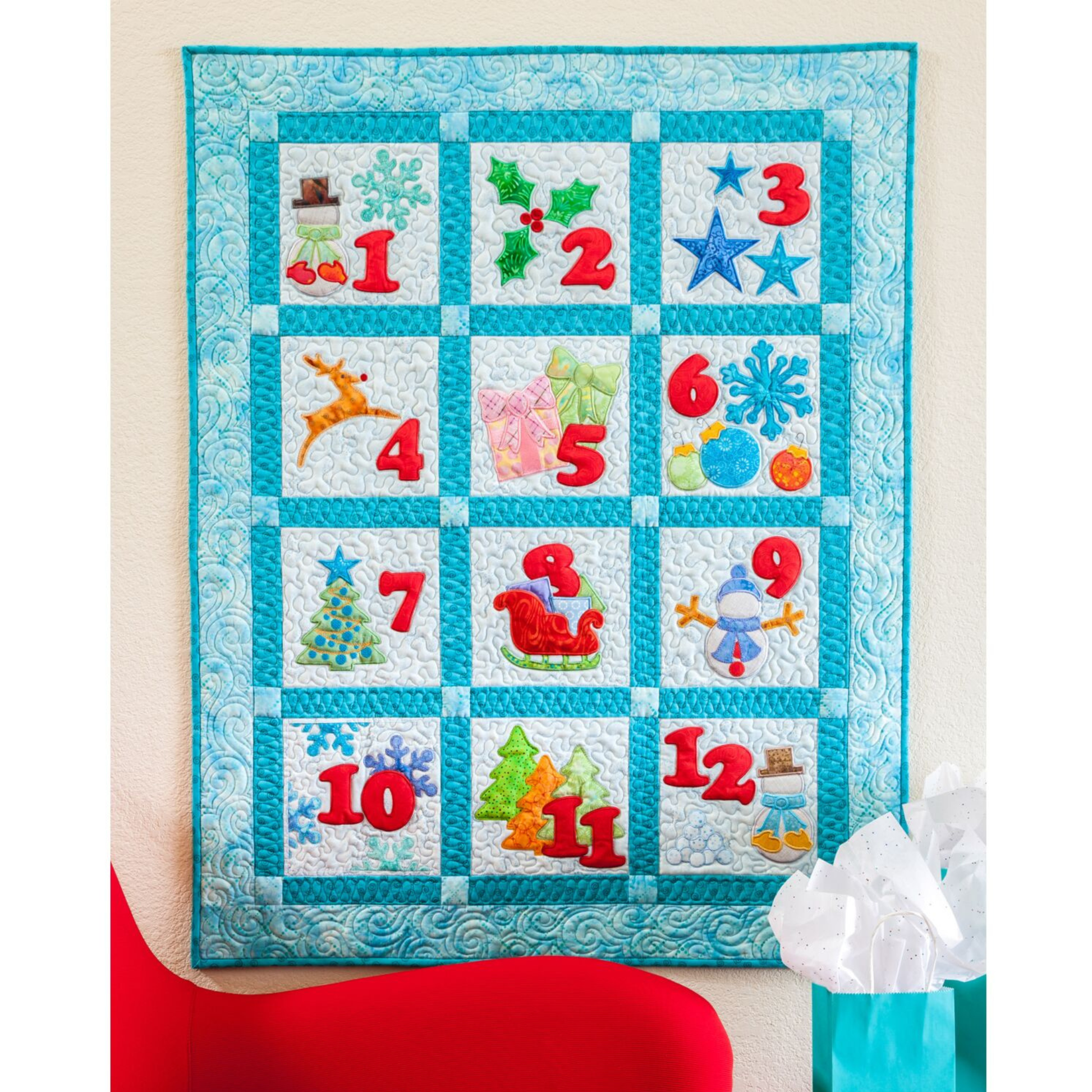 AccuQuilt GO! Carefree Numbers 1-12 Christmas countdown quilt with festive icons, hung with gifts