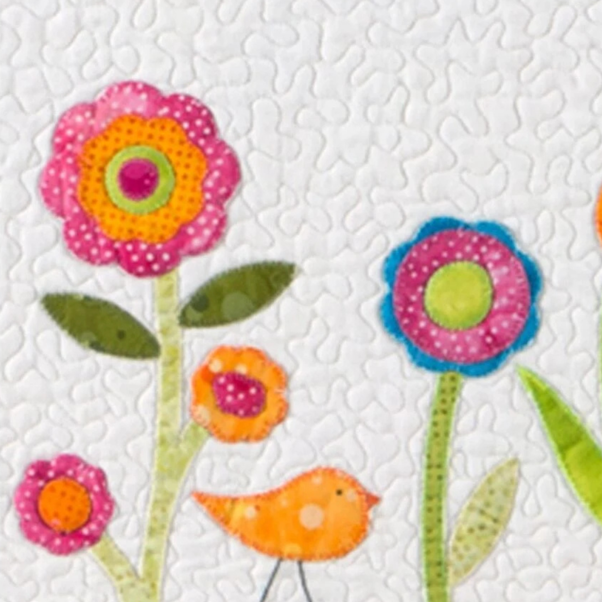 AccuQuilt GO! Crazy Petals layered circle flowers in pink, orange and blue with a bird, on a quilted block