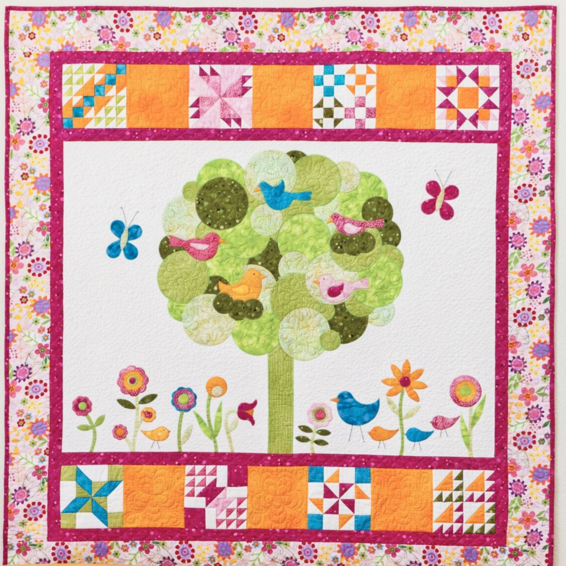 AccuQuilt GO! Crazy Petals forming a green circle tree with birds, butterflies and a pieced star border