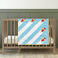 Pale blue and white baby quilt with red and yellow Airplane blocks draped over a wooden cot