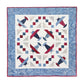 Square quilted wall hanging with Airplane blocks in red, navy and blue, framed by a patterned blue border