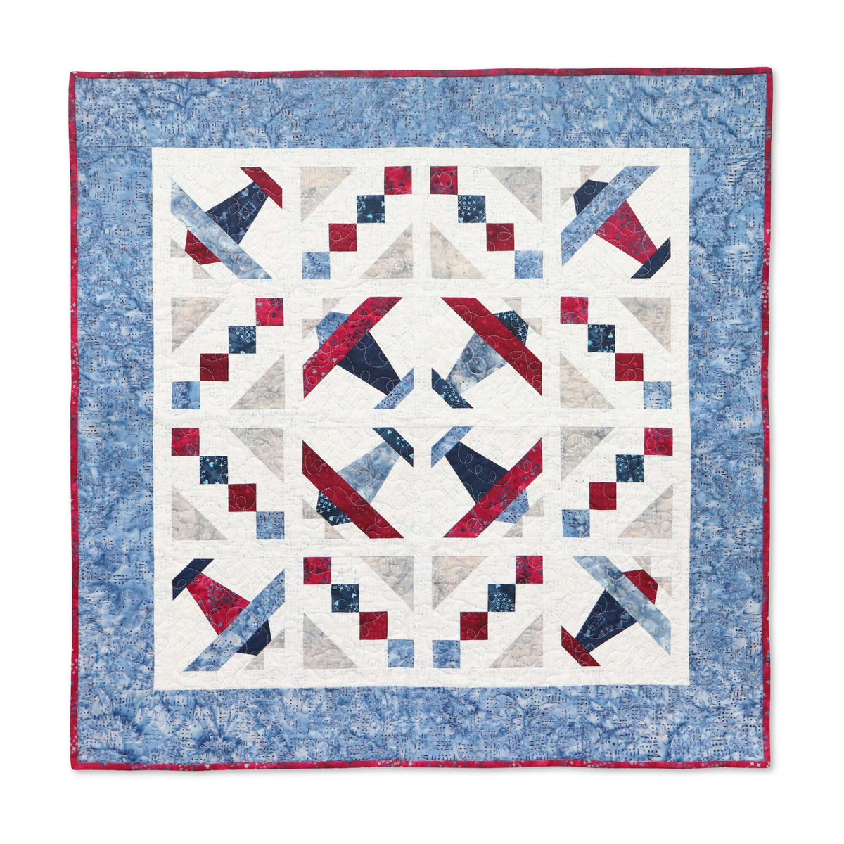 Square quilted wall hanging with Airplane blocks in red, navy and blue, framed by a patterned blue border