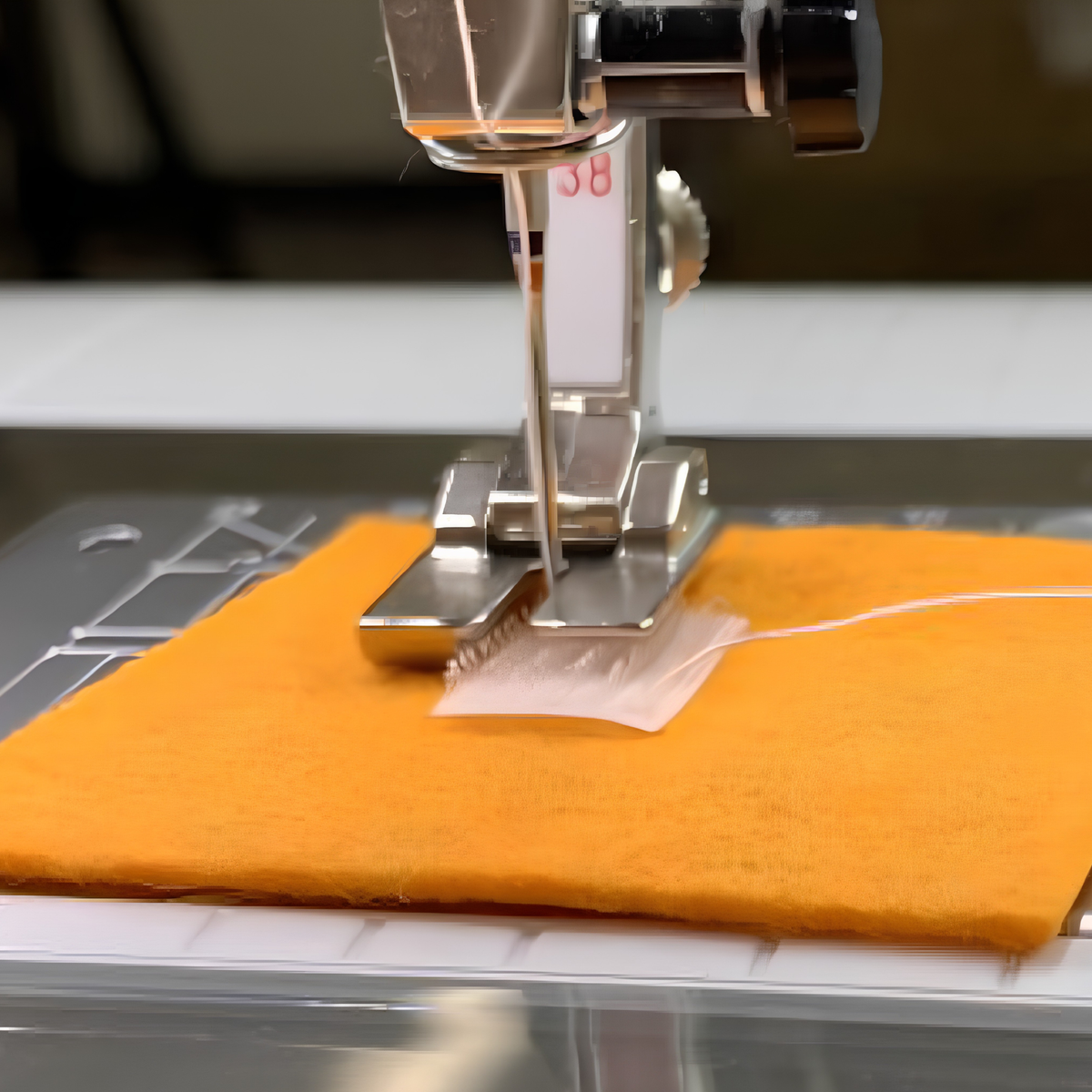 Close-up of a sewing machine bi-level presser foot stitching Velcro onto another fabric.