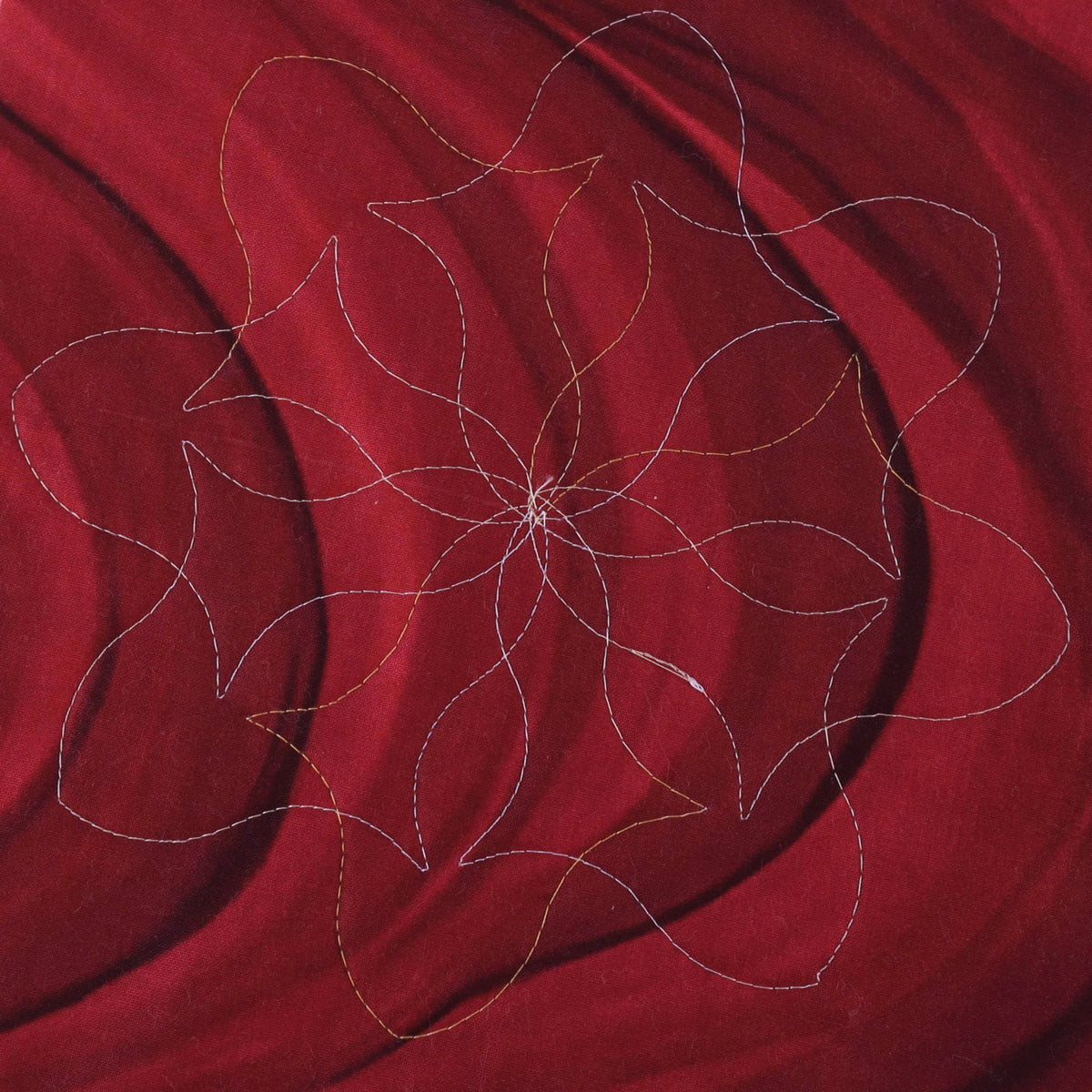 Rotated pointed bracket floral quilting motif stitched on red fabric
