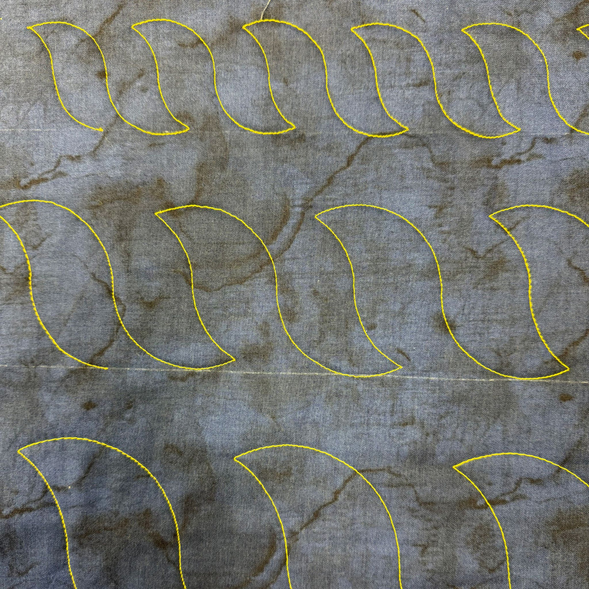 Separate rope quilting motifs in different sizes stitched in yellow thread on grey patterned fabric