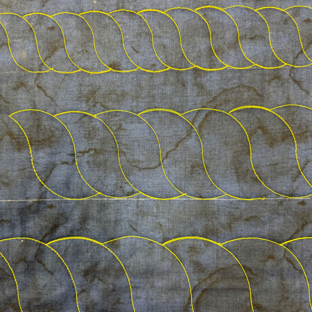 Continuous rope quilting borders in different sizes stitched in yellow thread on grey patterned fabric