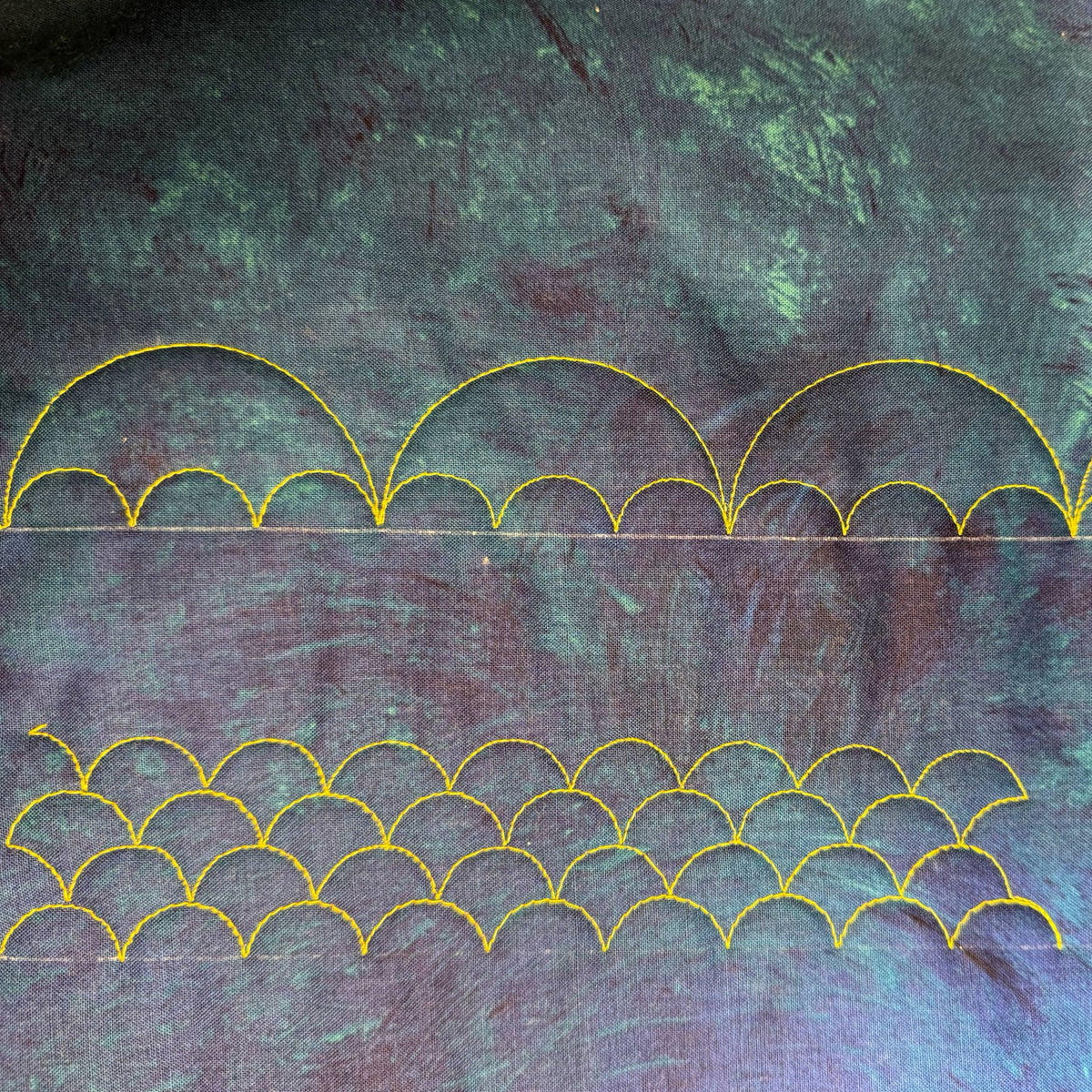 Clamshell background quilting and combined-size scalloped borders stitched in yellow thread on multicoloured fabric