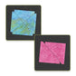 Two square coasters with textured patterns on black backing