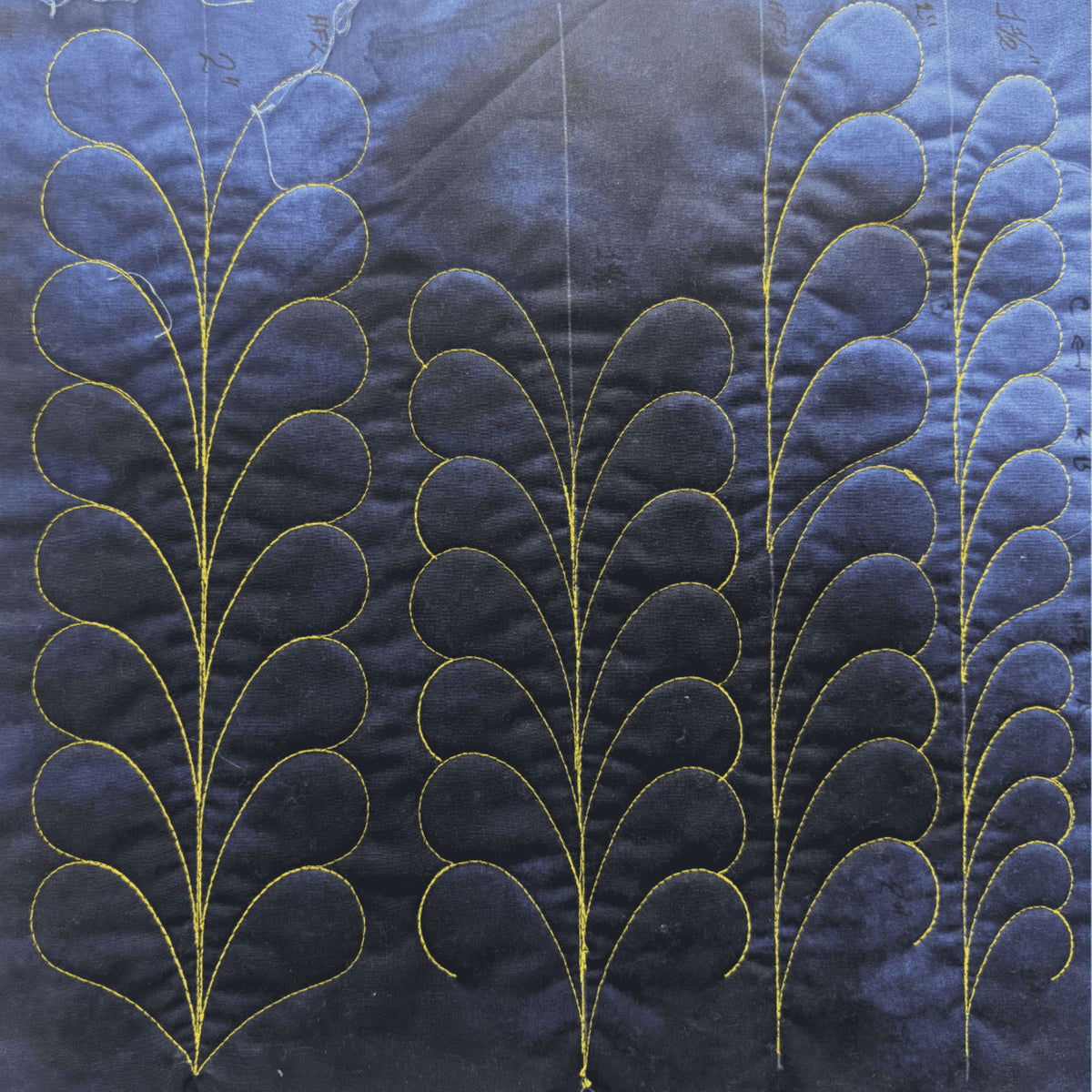 Heirloom sample on blue fabric with gold thread