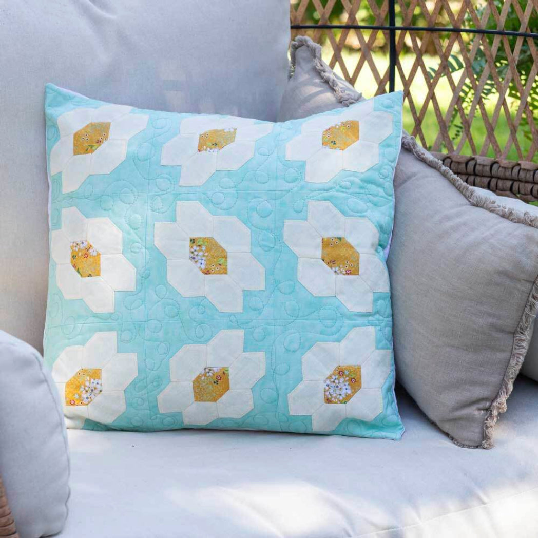 Pale blue quilted cushion cover featuring white and gold honeycomb English Paper Piecing flower blocks made with the AccuQuilt GO! Honeycomb die