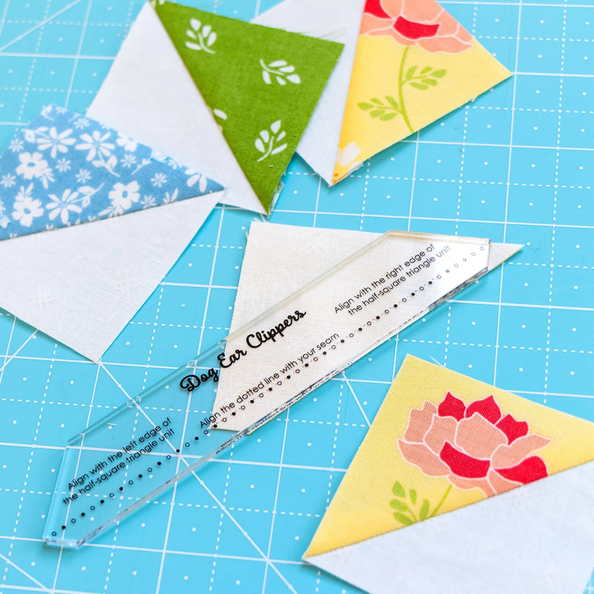 It's Sew Emma Dog Ear Clippers guide aligned on a half-square triangle unit for trimming fabric corners