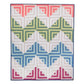 Baby quilt made from Log Cabin blocks, with rows of coral, green, blue and pink designs against a white background.