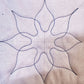 Eight-point decorative quilting motif stitched in dark thread on white fabric