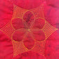 Nested flame petal sample on red fabric with gold thread
