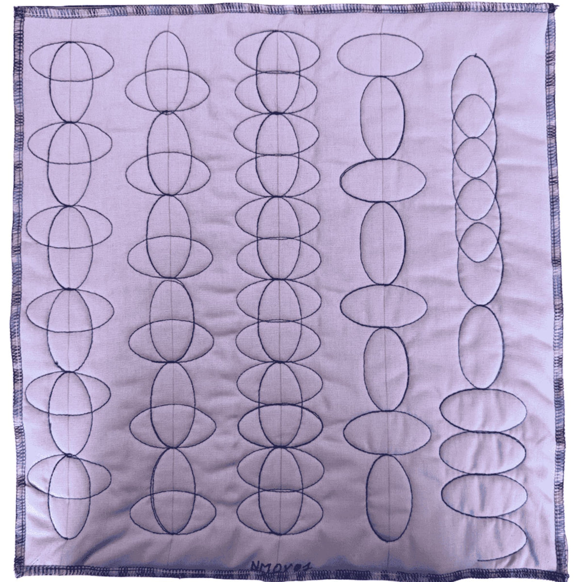 Rows of alternating and overlapping oval quilting borders stitched in dark thread on pale fabric