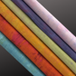 Colourful fabric bolts arranged in a row on a dark background