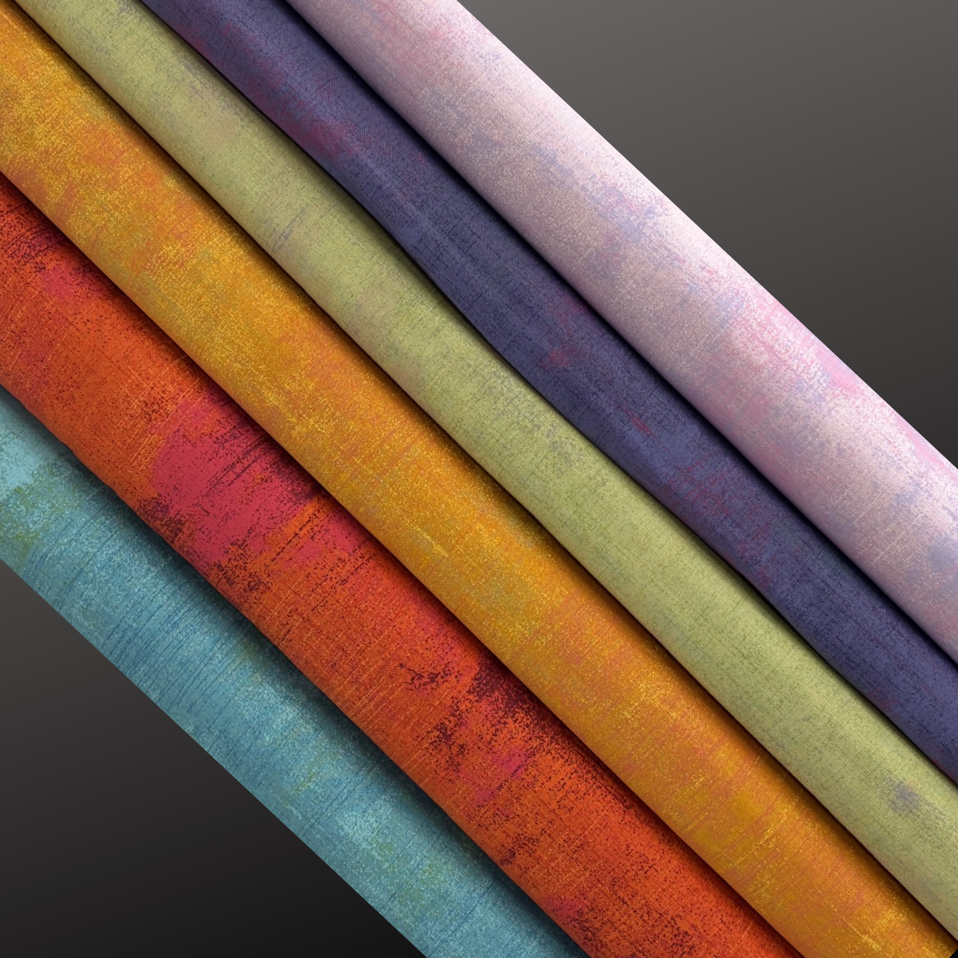 Colourful fabric bolts arranged in a row on a dark background