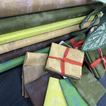 Stack of green and brown fabric swatches with a focus on texture and color variation.