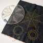 Quilter's Rule Mystifying Spider Web quilting template with yellow stitched web and circular designs on black fabric