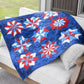 Finished quilt draped over a patio sofa showing repeating double star blocks made with the AccuQuilt GO! Double Star die in red, white and blue fabrics on a navy background, with diamond quilting detail