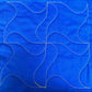 Swirl sample on blue fabric with gold thread