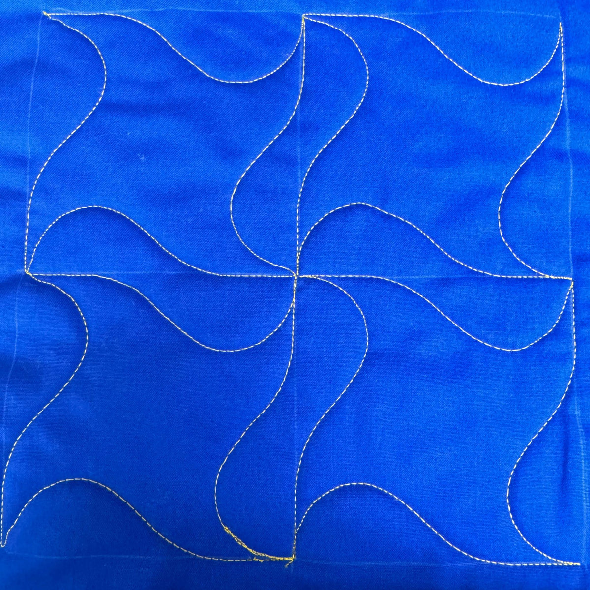 Swirl sample on blue fabric with gold thread
