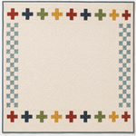 Cream quilt with a border of multicoloured plus sign blocks in red, navy, green, gold, and blue-grey on a white background, with a slate blue binding