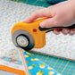 Hand using a rotary cutter on fabric with a cutting mat underneath