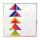 Rainbow strip-pieced flying geese quilt with five stacked triangle blocks in vibrant multicolour batik fabrics on a white background, finished with a rainbow striped binding